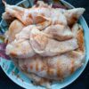 Close-up of raw chicken breasts seasoned, ready for cooking, on a decorative plate.
